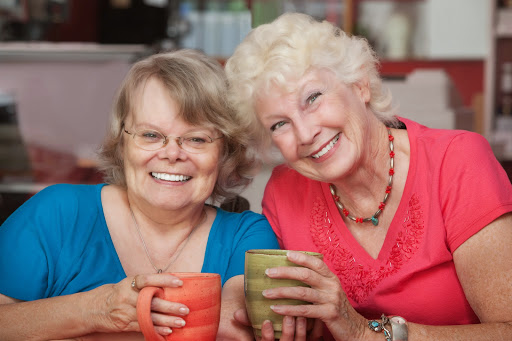 Two joyful friends enjoying a cozy moment over coffee.