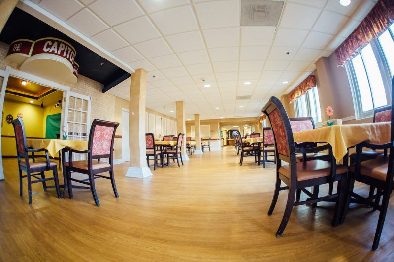 An empty restaurant dining area with wooden floors and neatly arranged tables and chairs.