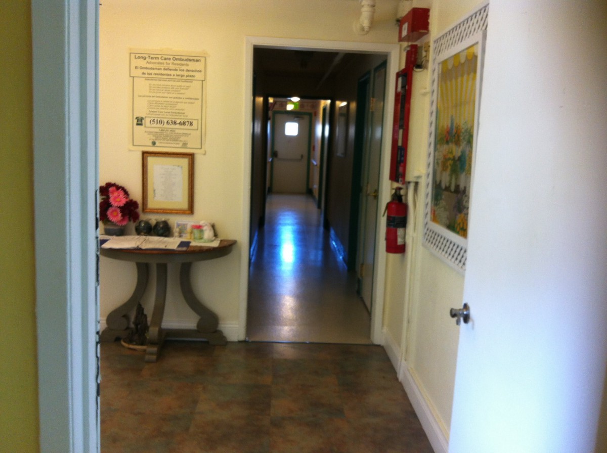 A view of an interior hallway with doors on either side, featuring a small table and a fire extinguisher mounted on the wall.