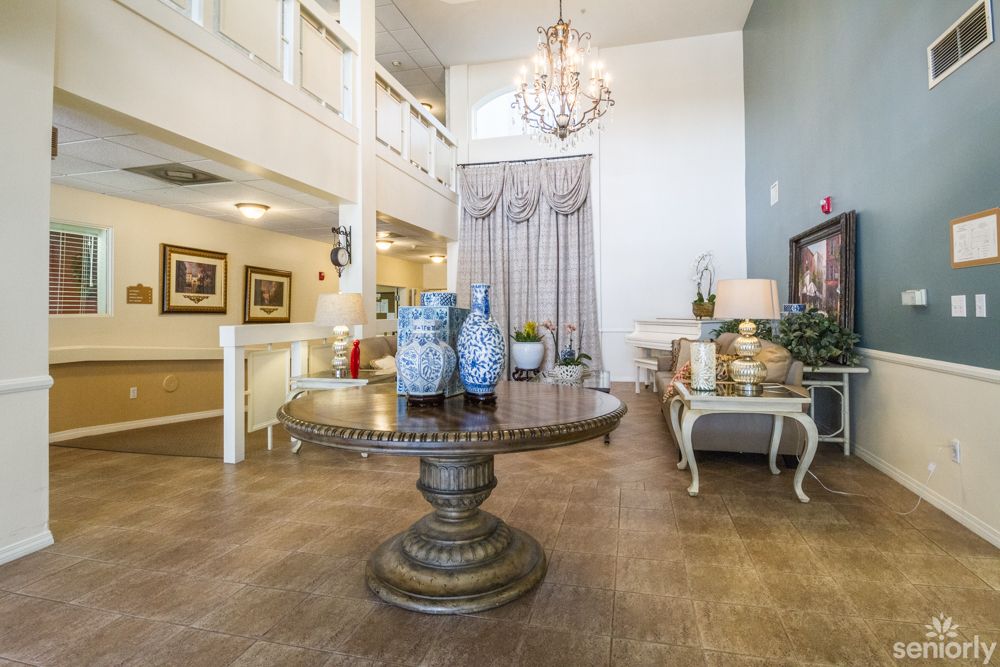 A beautifully decorated lobby featuring a round table with blue vases, surrounded by elegant furnishings and a chandelier.