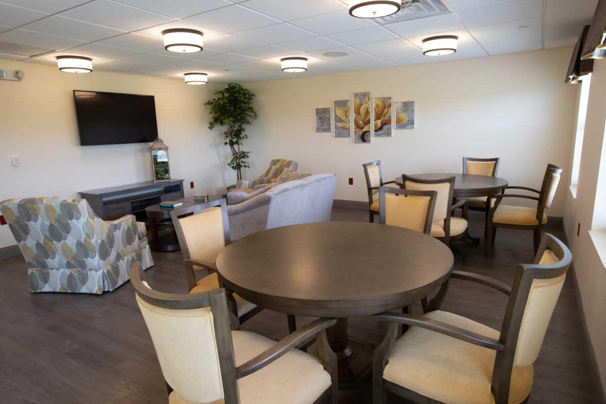 A cozy lounge area featuring round tables, chairs, a TV, and comfortable seating.
