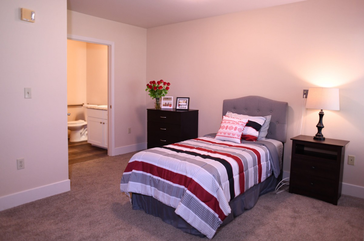Cozy bedroom with a single bed, featuring striped bedding and decorative pillows.