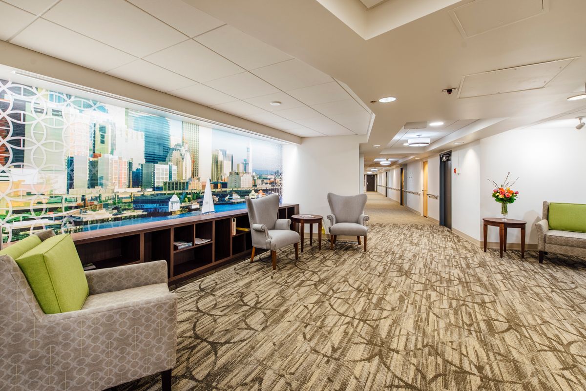 A modern hotel corridor with comfortable seating and artwork on the wall.