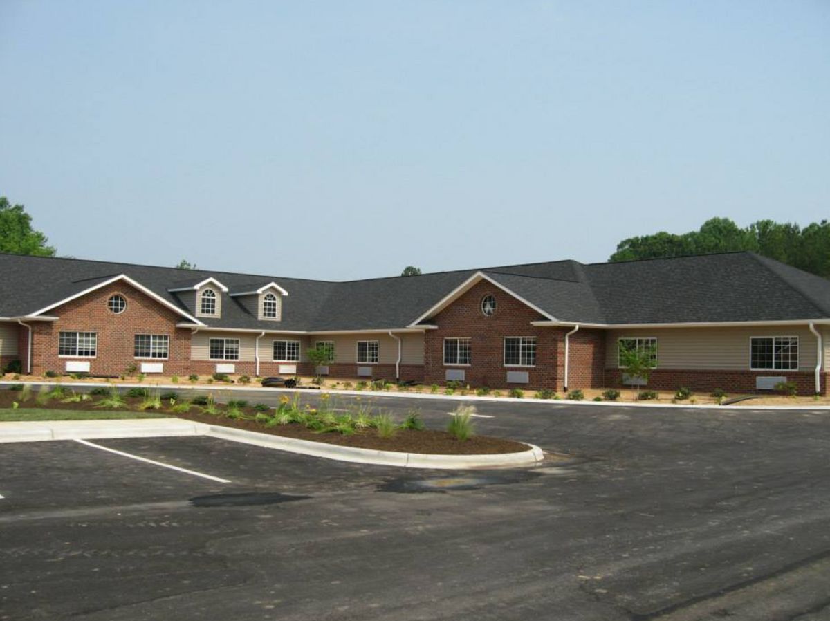 A single-story brick building with a dark roof, adjacent to an empty parking lot.