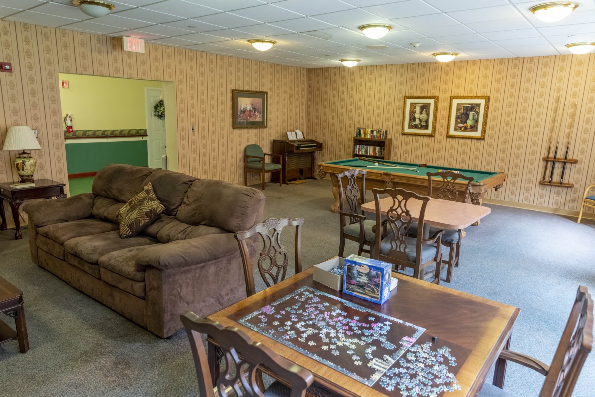 A cozy living room with a sofa, tables, and chairs, featuring a puzzle in progress.