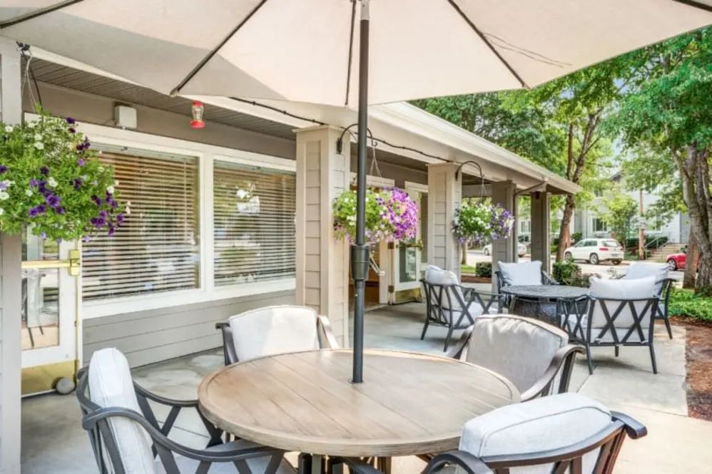 A cozy outdoor seating area with a round table and umbrella, perfect for dining.