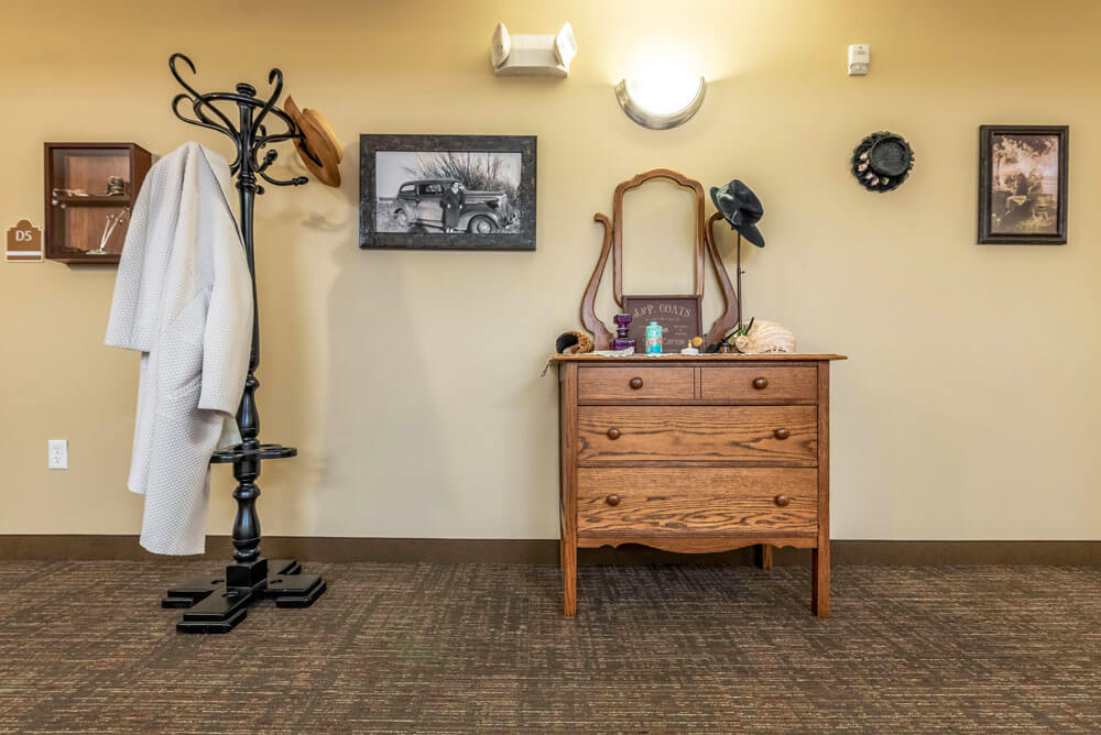 A cozy room with a vintage dresser and mirror, accompanied by a coat rack and wall decor.
