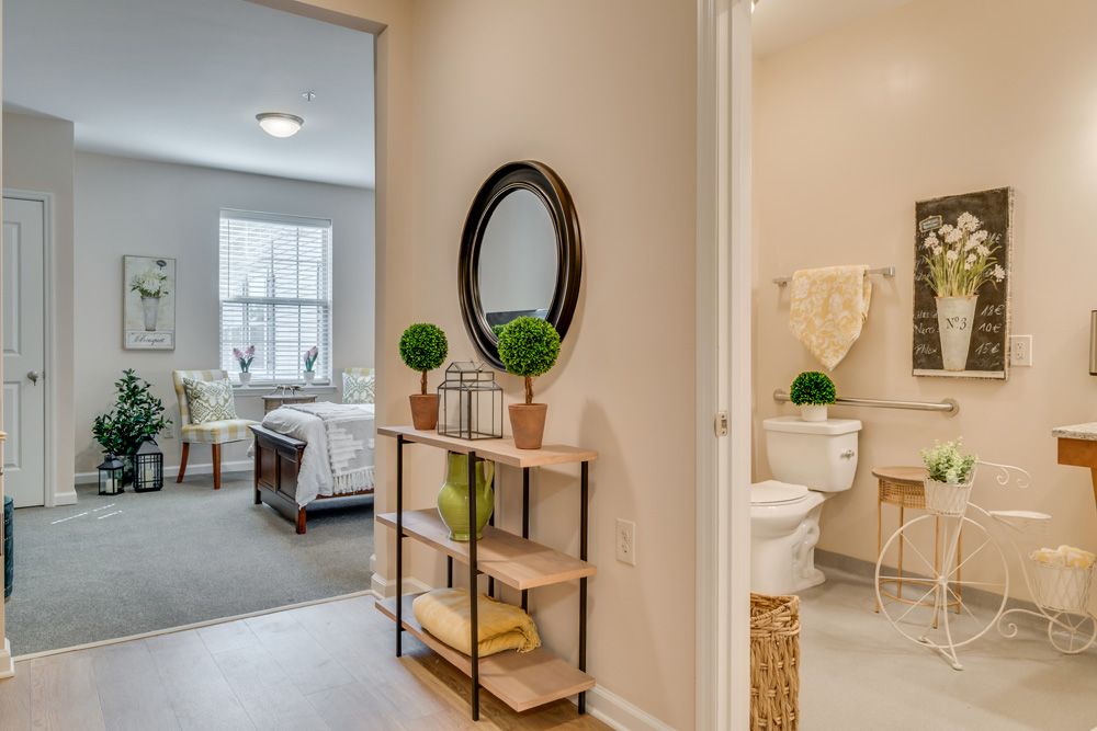 A cozy hallway leading to a bedroom and bathroom, featuring a decorative mirror and plants.