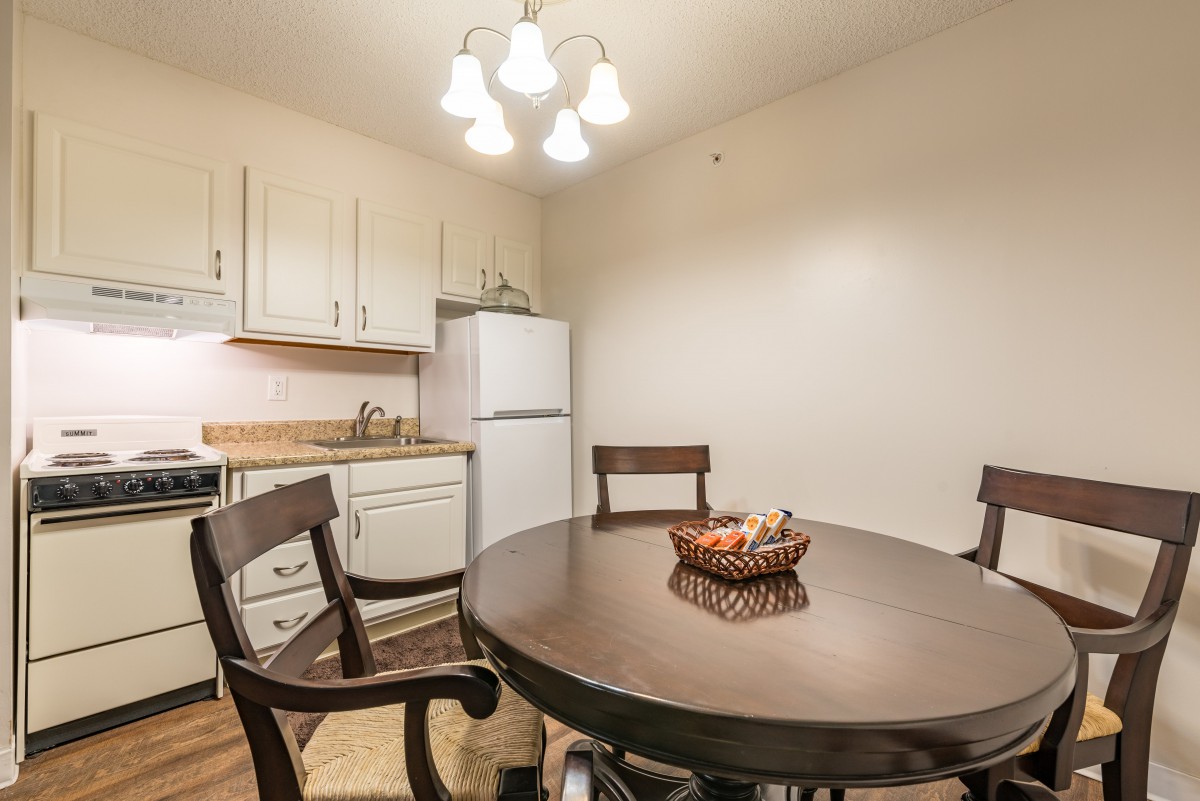 A cozy kitchen and dining area with a round wooden table, chairs, and a refrigerator.