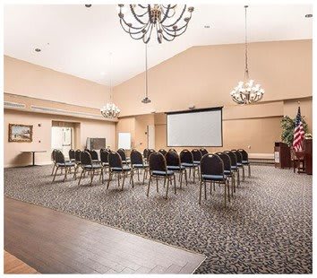 A spacious conference room with arranged chairs facing a projector screen.