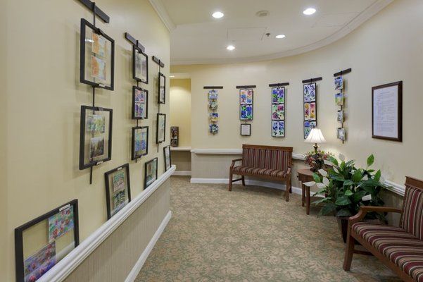 A hallway designed as an art gallery with framed pictures on the walls, a bench for seating, and decorative plants.