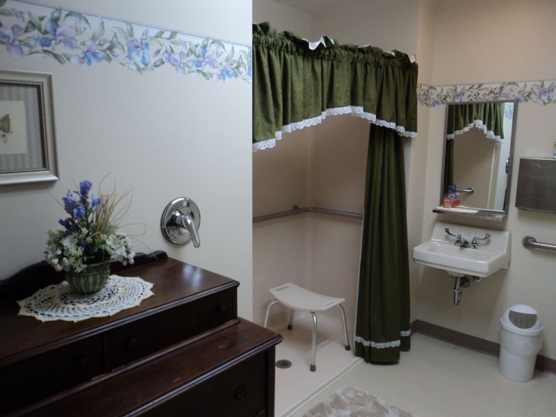 A bathroom with a shower area featuring a green curtain, a sink, and floral decorations.