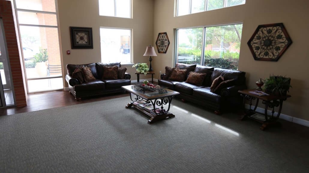 A spacious living room with large windows, featuring two sofas and a decorative coffee table.