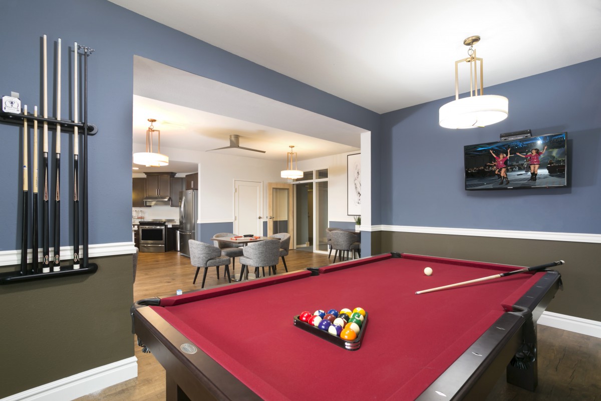 A modern game room featuring a red pool table and stylish furnishings.