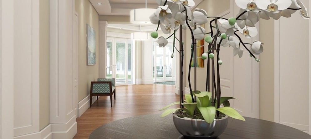 A modern hallway with a decorative orchid arrangement and wood flooring.