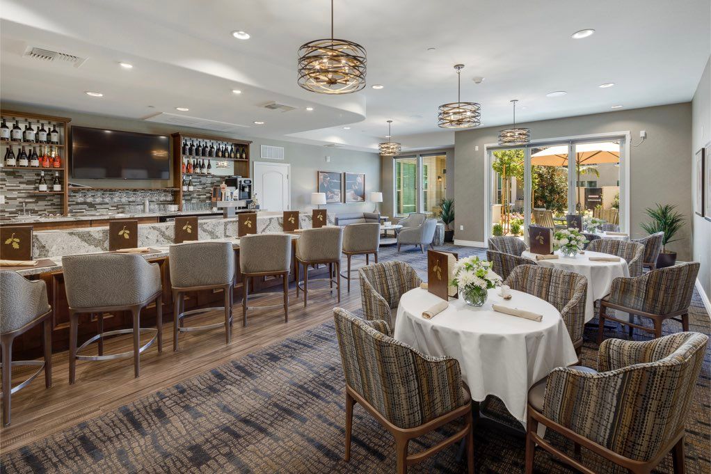 A modern dining and bar area with elegant chandeliers and neatly arranged tables.