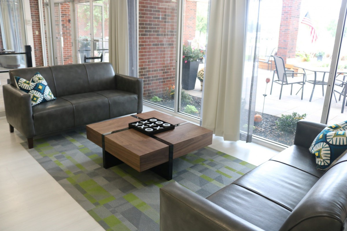 A modern living room with leather sofas, a wooden coffee table, and large windows.