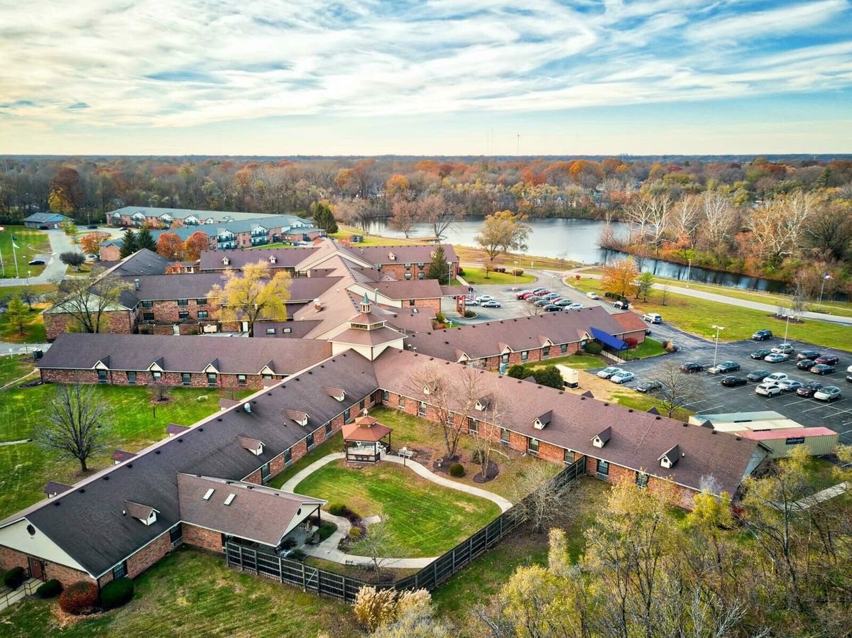 Aerial view of a large building complex surrounded by autumn foliage near a river.