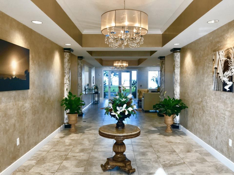 A luxurious lobby featuring a chandelier, decorative table, and greenery.