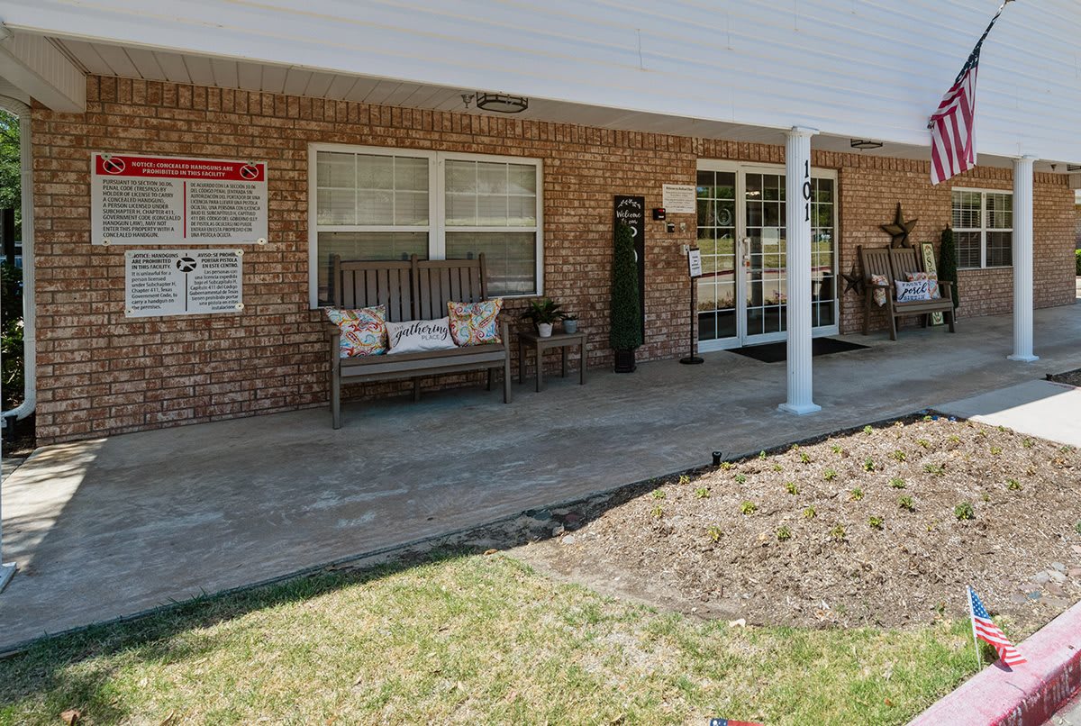 A cozy porch with a bench and brick wall, ideal for outdoor relaxation.