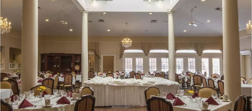 Elegant banquet hall set up for a wedding reception with a chandelier and decorated tables.