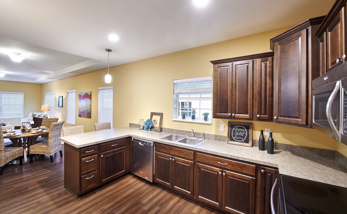 A modern kitchen with wooden cabinets, a sleek countertop, and ample lighting.