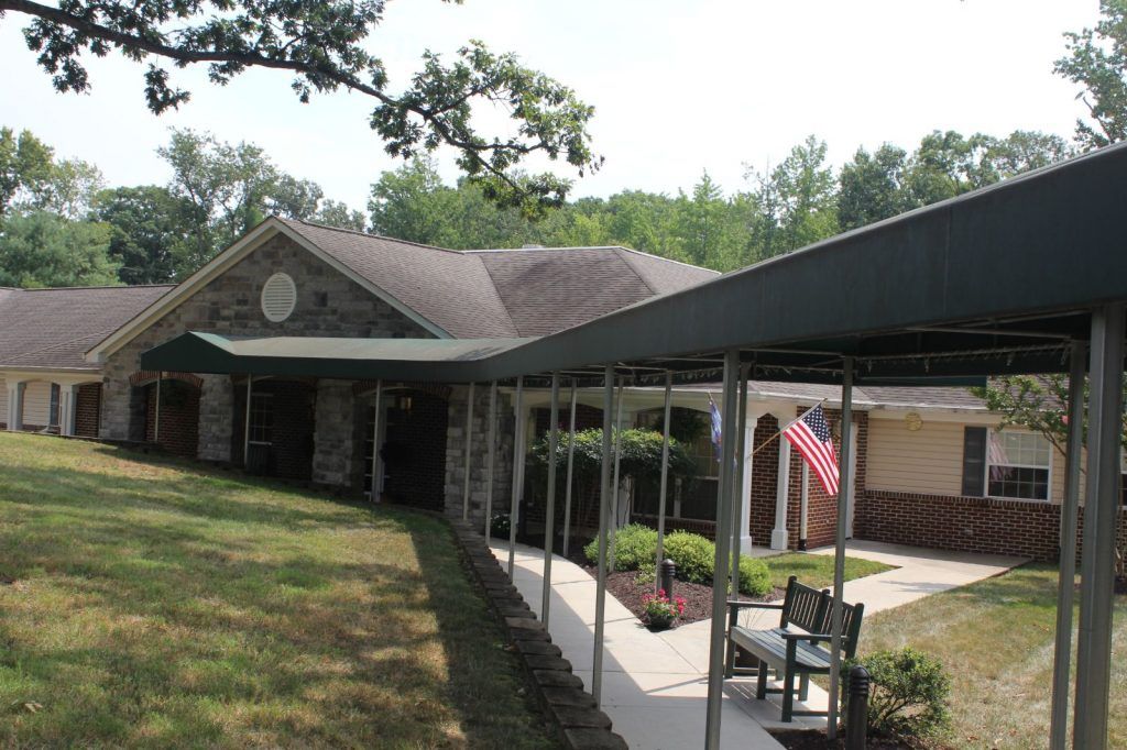 A suburban house with a covered pathway and a garden area, featuring an American flag.