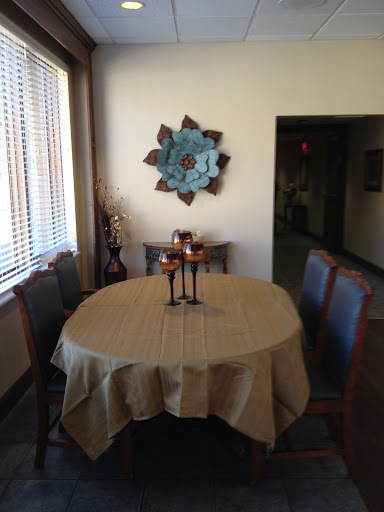 A cozy dining area featuring a round table set with candle holders, surrounded by wooden chairs and adorned with decorative wall art.
