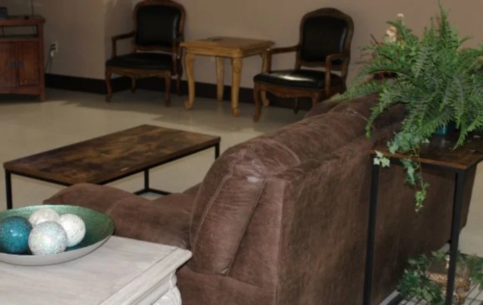 A waiting room with a brown couch, chairs, and a small table.