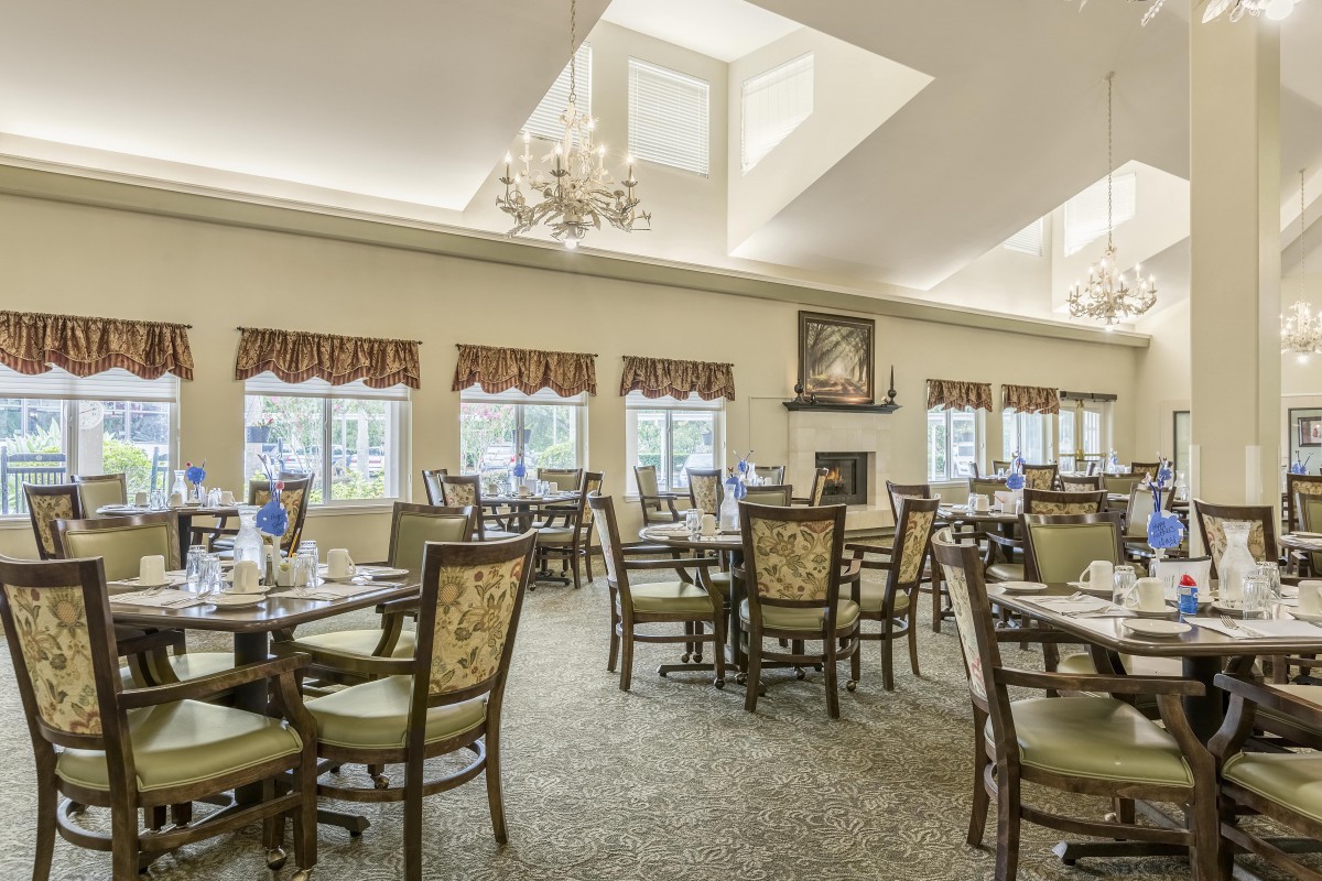 A spacious dining area with elegant furniture and a chandelier.