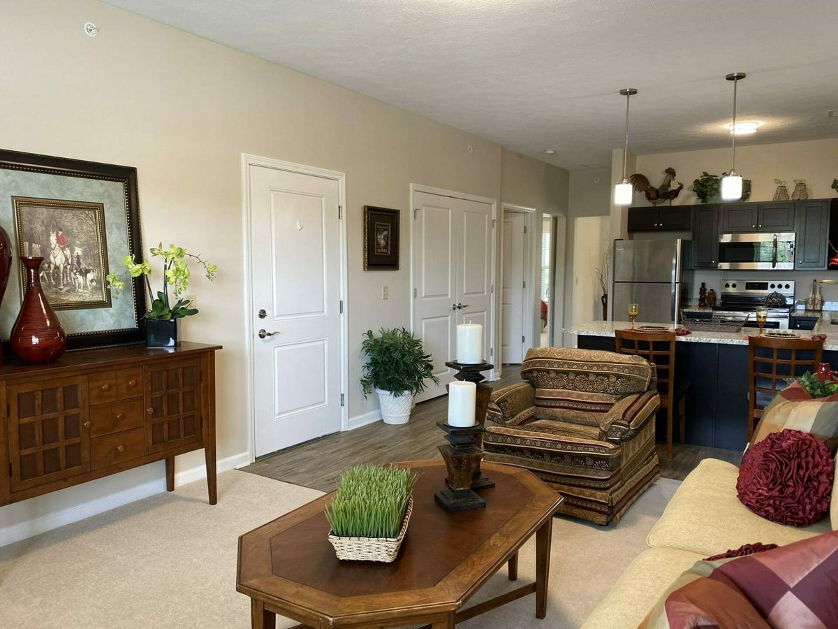 A modern living room with an open layout leading to the kitchen, featuring stylish furniture and decor.