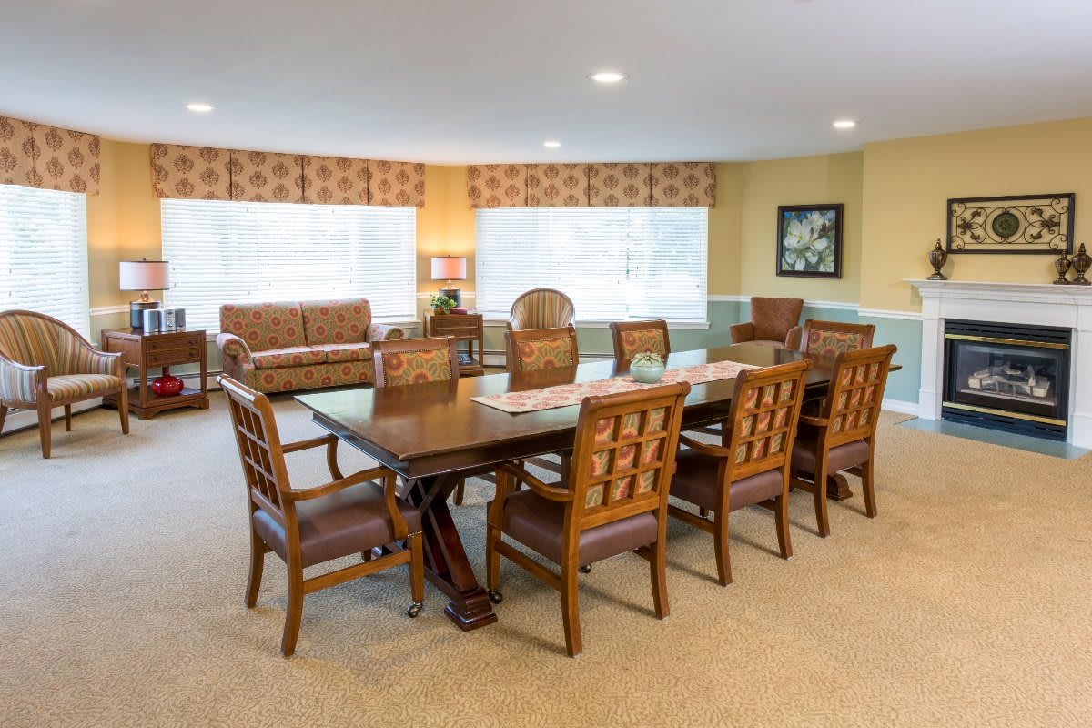 A spacious dining room with a large table and multiple chairs, featuring ample natural light from the windows.