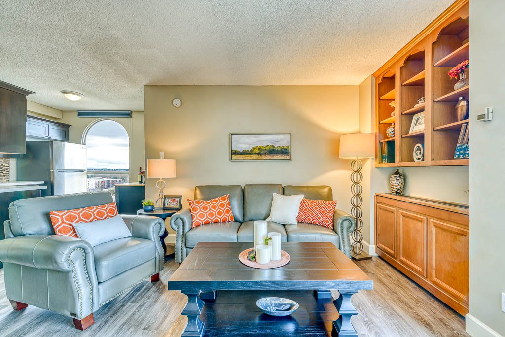 A cozy living room with a sofa, armchair, and bookshelves filled with decor.
