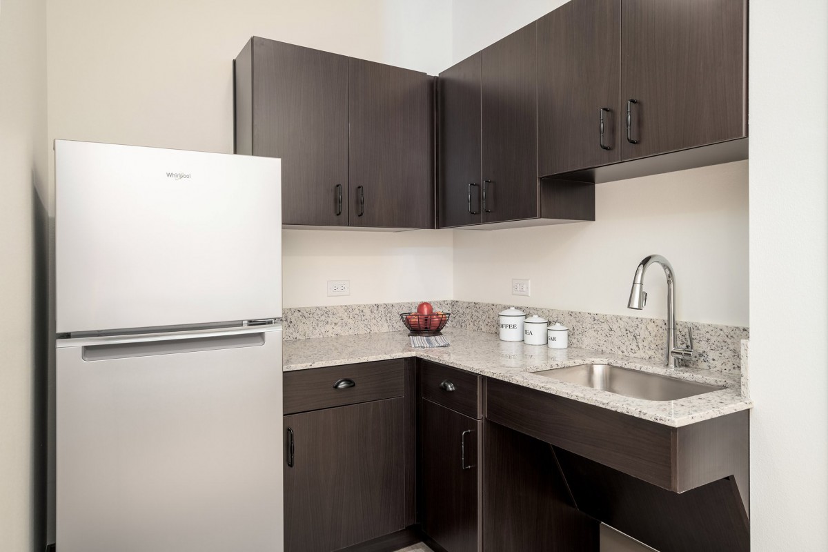 A modern kitchen with dark cabinets and a white refrigerator.