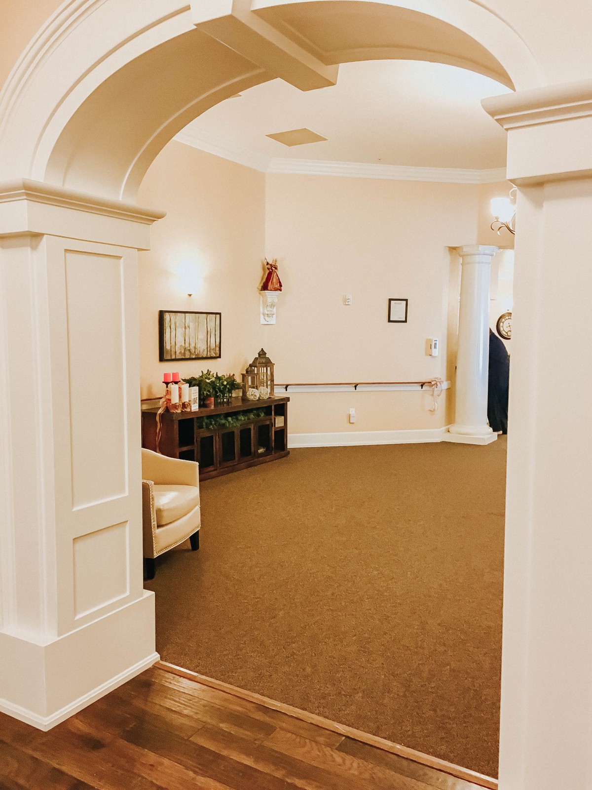 A cozy interior space with an archway leading to a hallway, featuring comfortable seating and decorative elements.