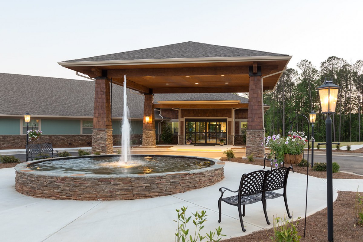A modern building entrance featuring a decorative fountain and benches.