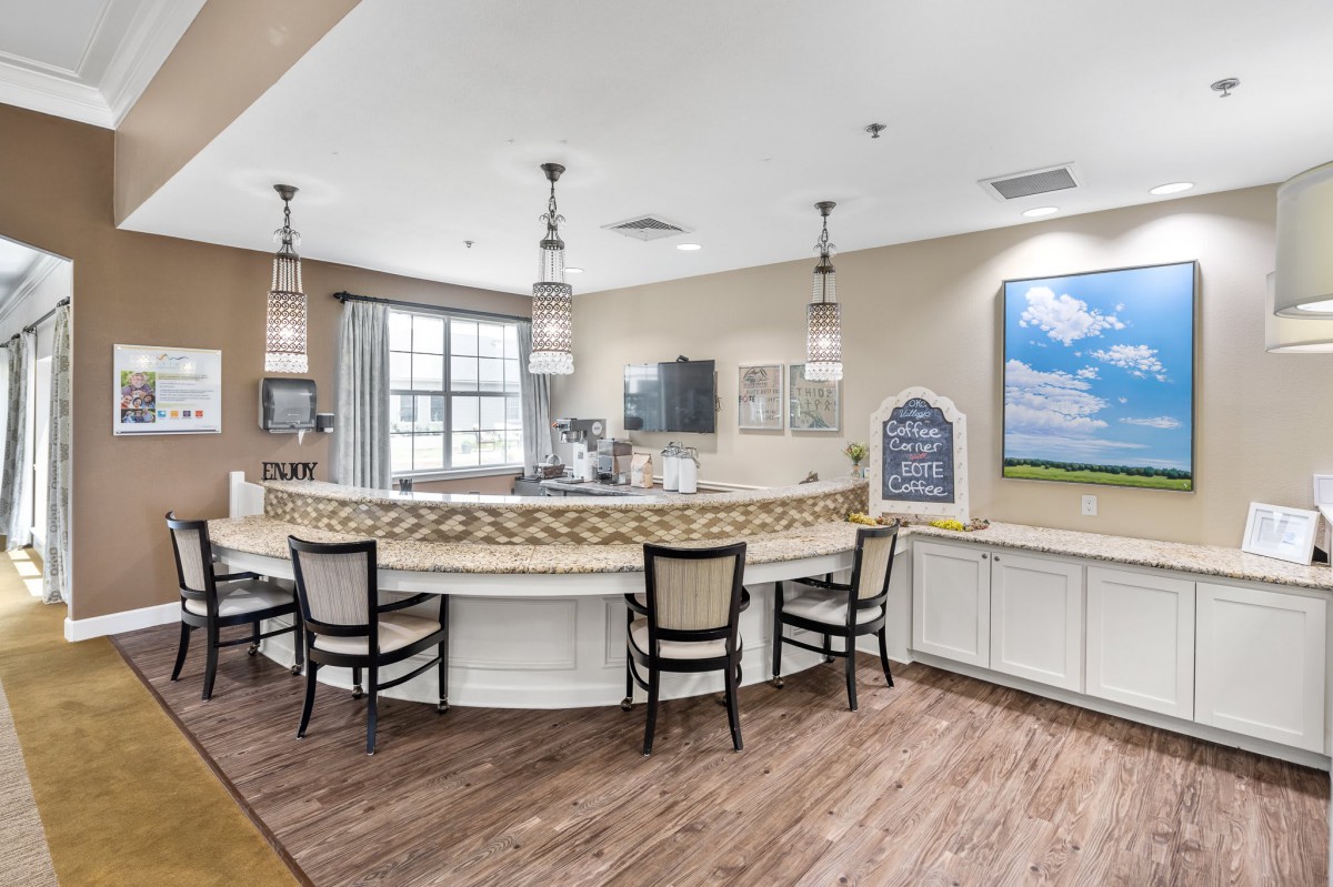 A modern reception area with a semi-circular counter, surrounded by chairs and illuminated by pendant lights.