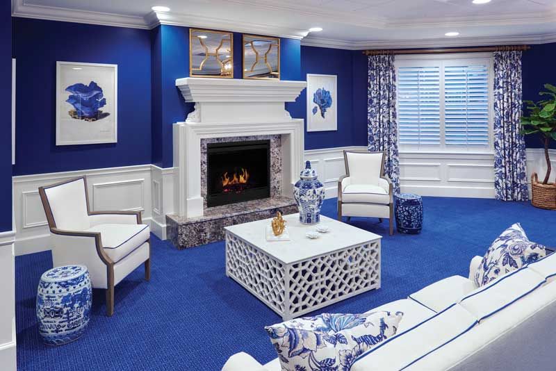A modern living room with blue and white decor, featuring a fireplace and stylish furniture.