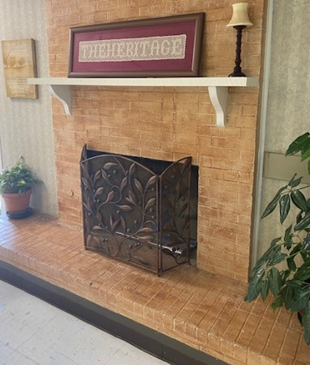A cozy fireplace with an ornate metal screen and decorative shelf above.