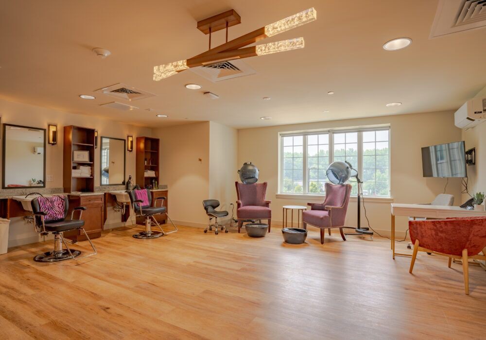 A modern hair salon interior with chairs and mirrors, featuring large windows and elegant lighting.