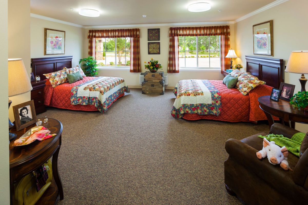 A cozy bedroom with two beds, colorful decor, and large windows.