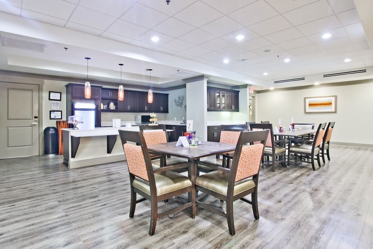 A modern dining area with neatly arranged tables and chairs, and a stylish bar counter in the background.