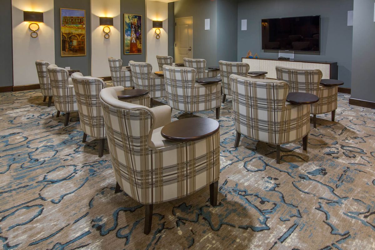 A cozy lounge with plaid chairs arranged around small tables on a patterned carpet.