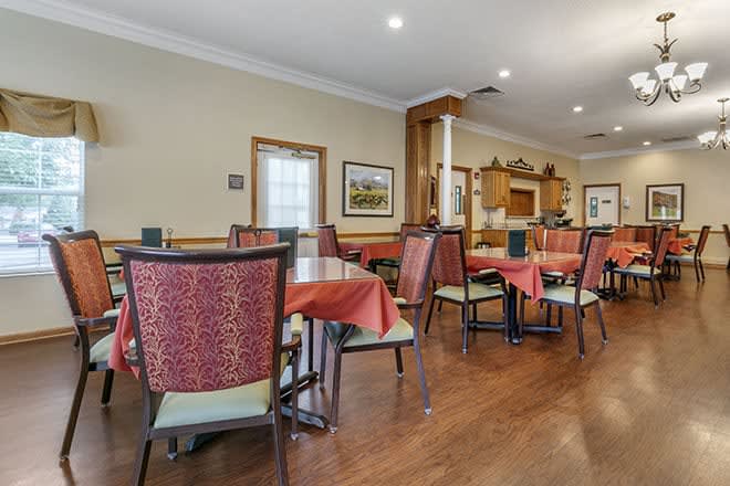 An empty dining room with tables and chairs set for guests.