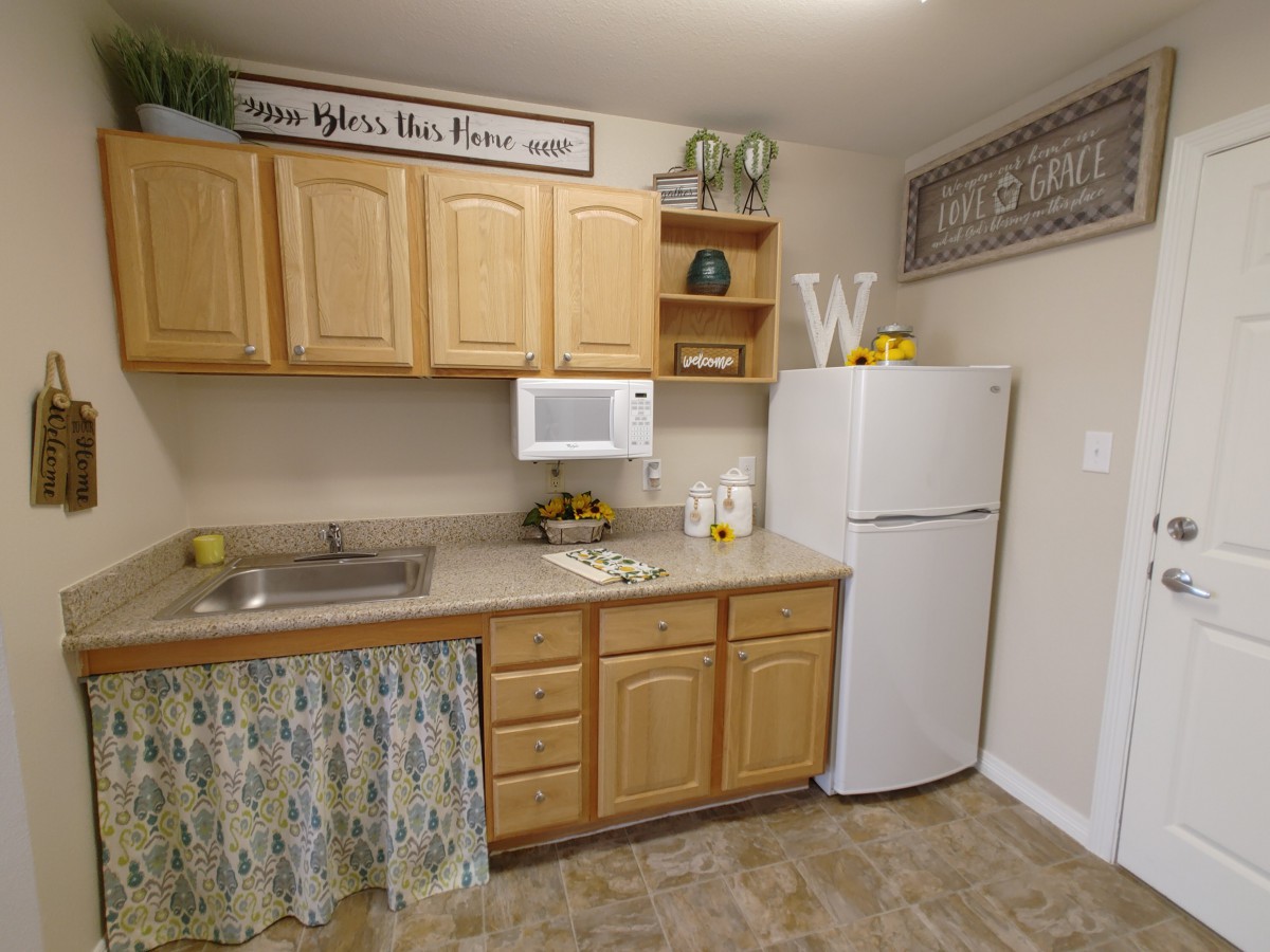 A cozy kitchen with wooden cabinets, a fridge, and decorative elements.