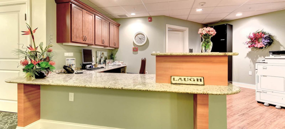 A welcoming reception desk with a 'LAUGH' sign and flowers.