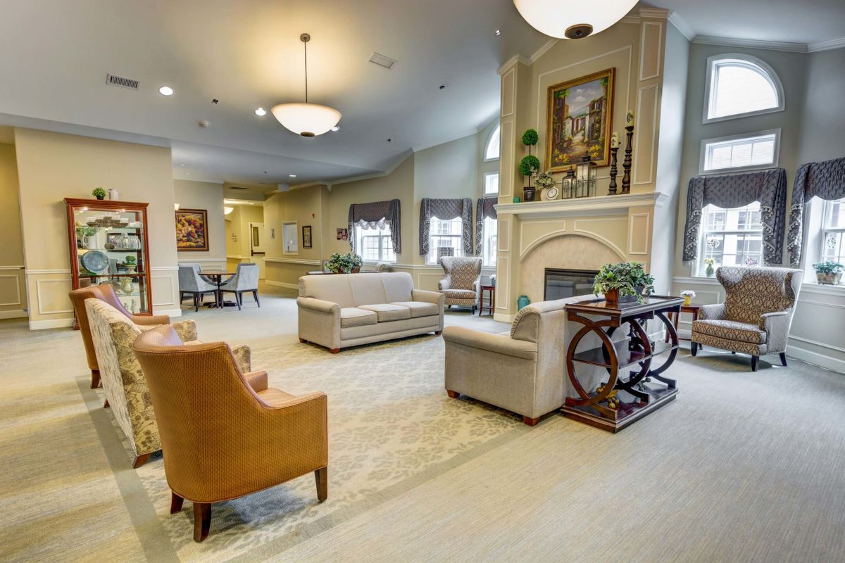 A spacious and elegantly furnished living room with sofas, a fireplace, and decorative chandeliers.