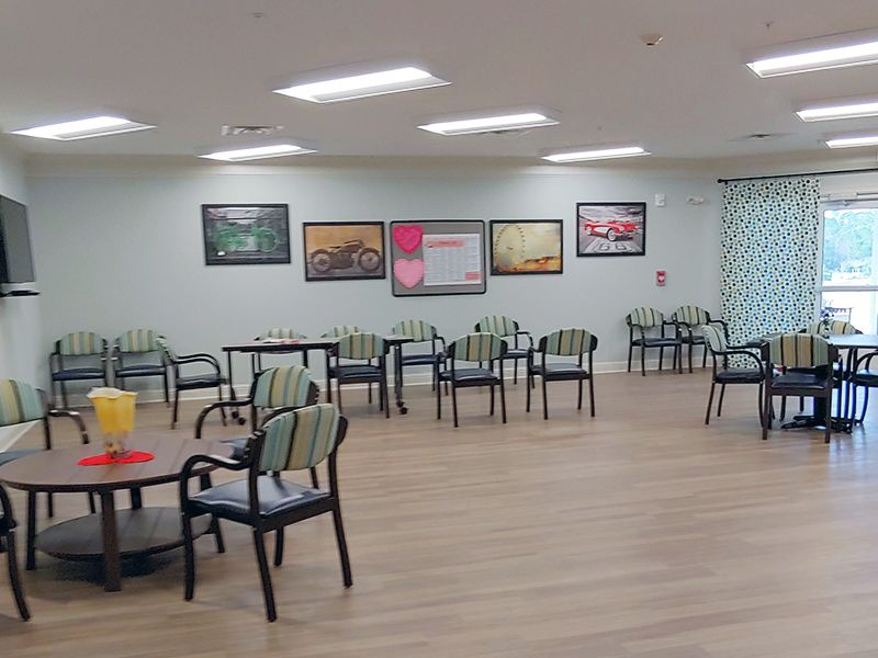 A spacious dining area with neatly arranged chairs and tables, adorned with colorful artwork on the walls.