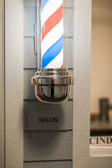 A classic barber pole with a spiral design outside a salon.