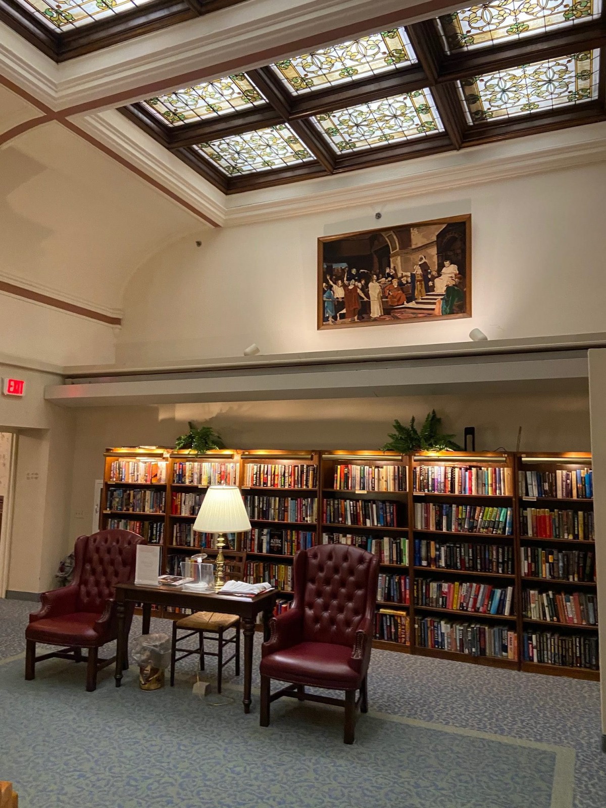 A cozy library reading nook with two leather chairs, a small table, and shelves filled with books.